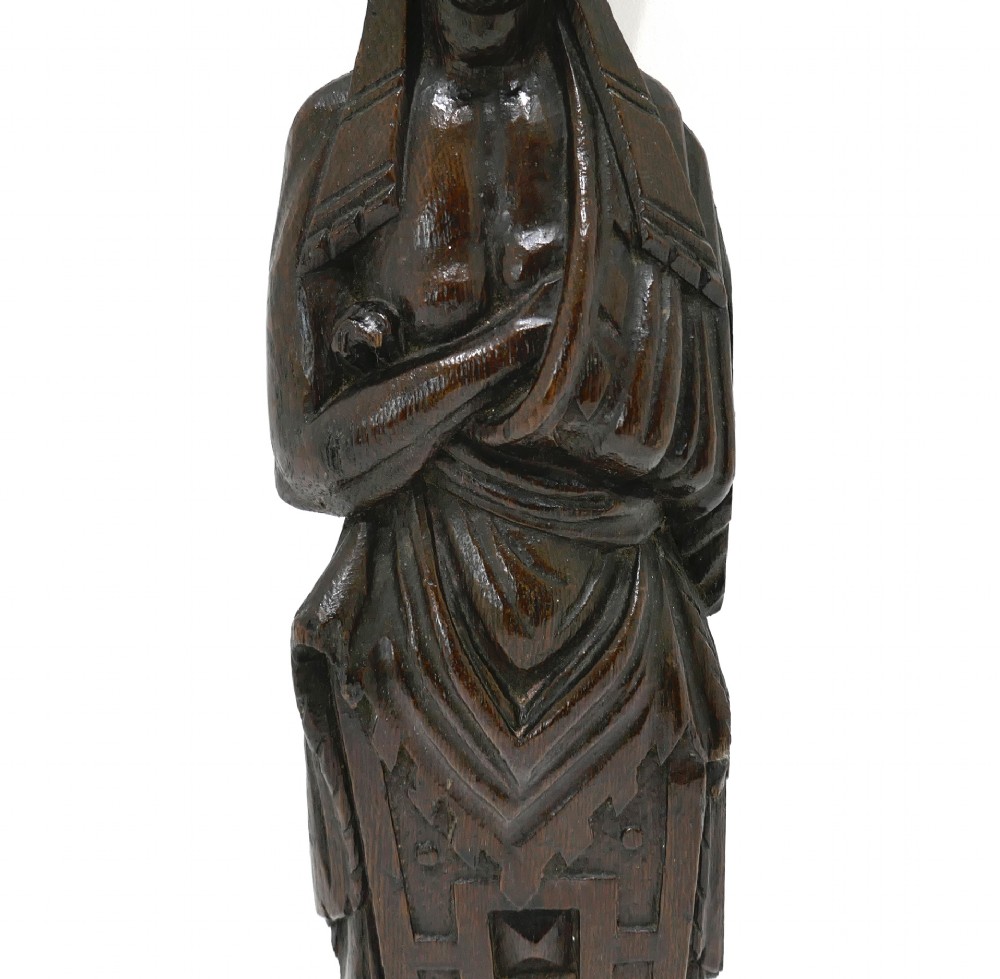 A dark seventeenth-century carved oak caryatid figure depicting a woman with crossed arms on a geometric strapwork base. View III