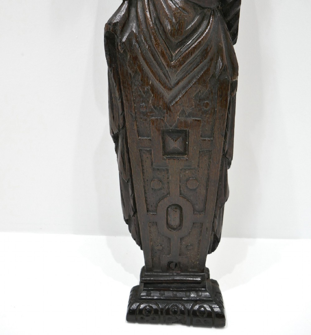A dark seventeenth-century carved oak caryatid figure depicting a woman with crossed arms on a geometric strapwork base. View IV