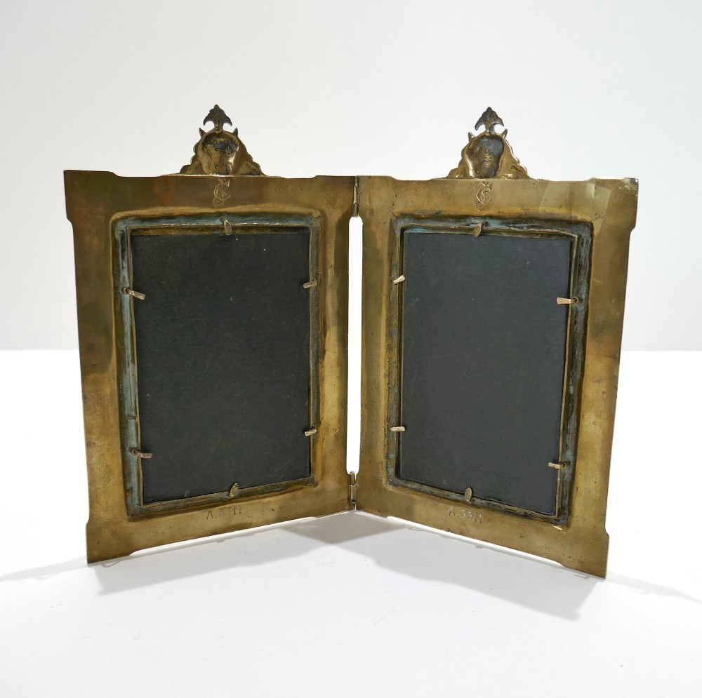 A late 19th-century Victorian double brass picture frame with ornate engraved geometric borders and classical mask finials. View V