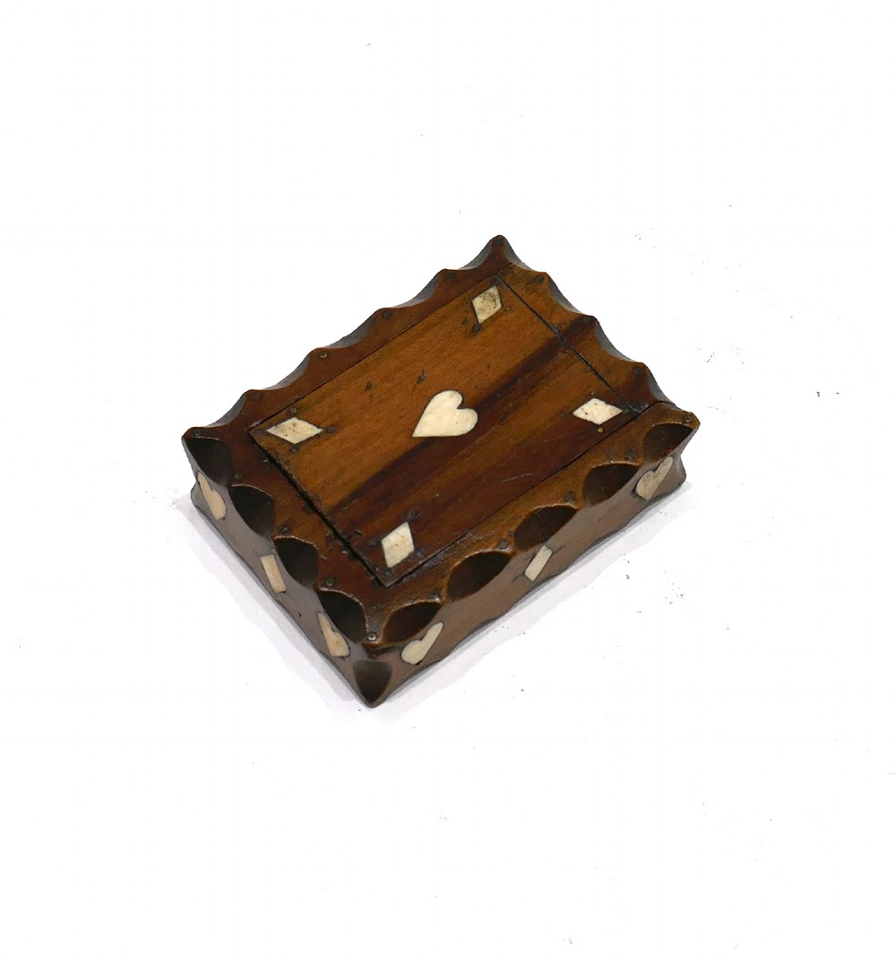 An antique nineteenth-century rectangular fruitwood snuff box featuring scalloped carved borders and inlaid bone heart and diamond shapes.