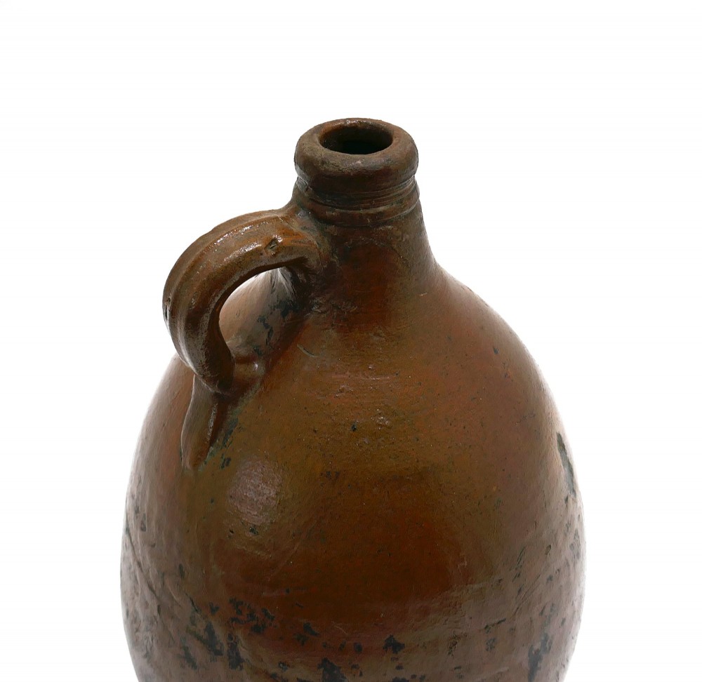 An 18th-century salt-glazed brown stoneware flagon featuring a bulbous body, narrow neck, loop handle, and an impressed number two on the shoulder. View V