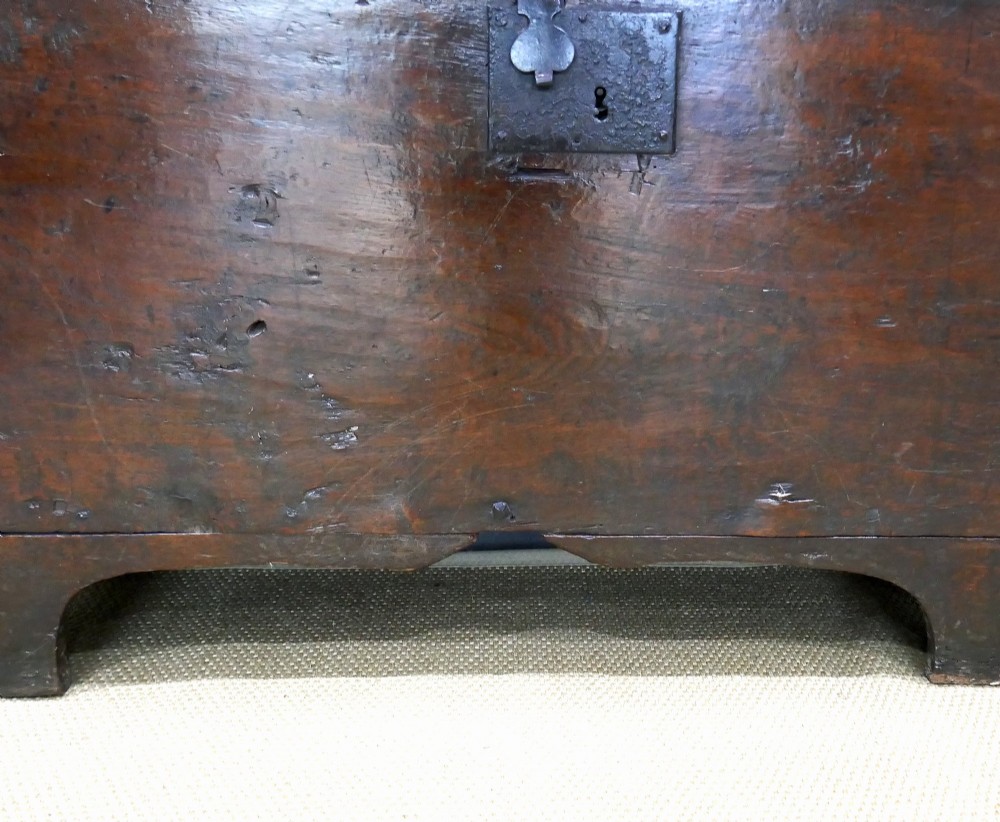 A sixteenth-century dark oak boarded coffer featuring a simple flat lid, an iron lockplate on the front panel, and a shaped lower apron. View II