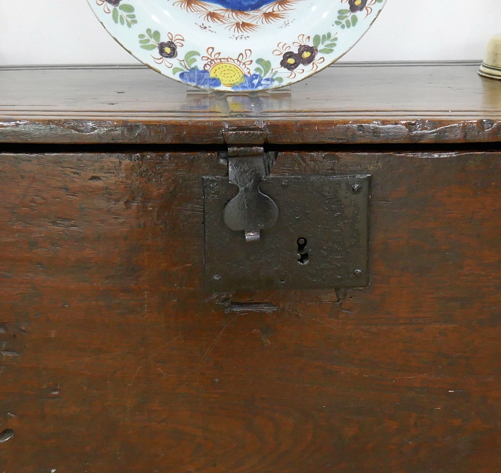 A sixteenth-century dark oak boarded coffer featuring a simple flat lid, an iron lockplate on the front panel, and a shaped lower apron. View III