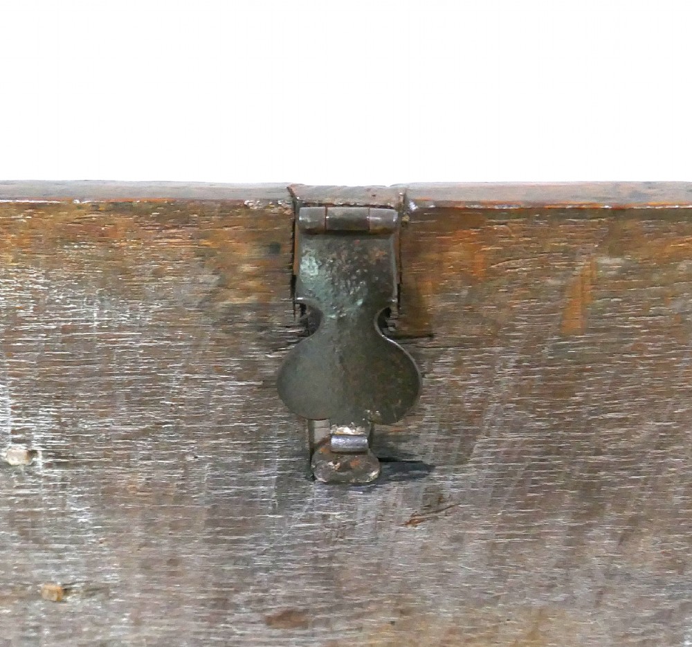 A sixteenth-century dark oak boarded coffer featuring a simple flat lid, an iron lockplate on the front panel, and a shaped lower apron. View V