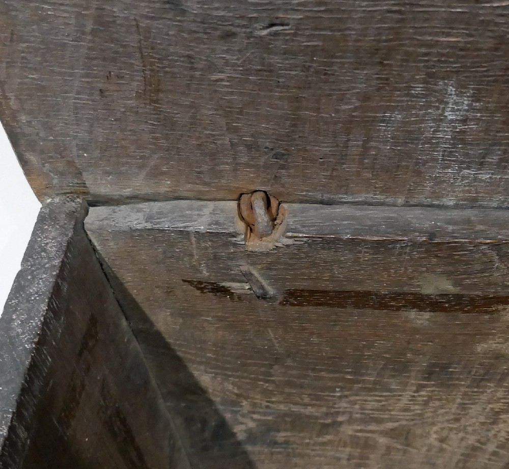 A sixteenth-century dark oak boarded coffer featuring a simple flat lid, an iron lockplate on the front panel, and a shaped lower apron. View VI