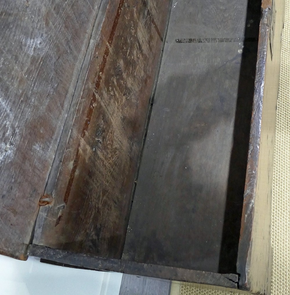 A sixteenth-century dark oak boarded coffer featuring a simple flat lid, an iron lockplate on the front panel, and a shaped lower apron. View VII