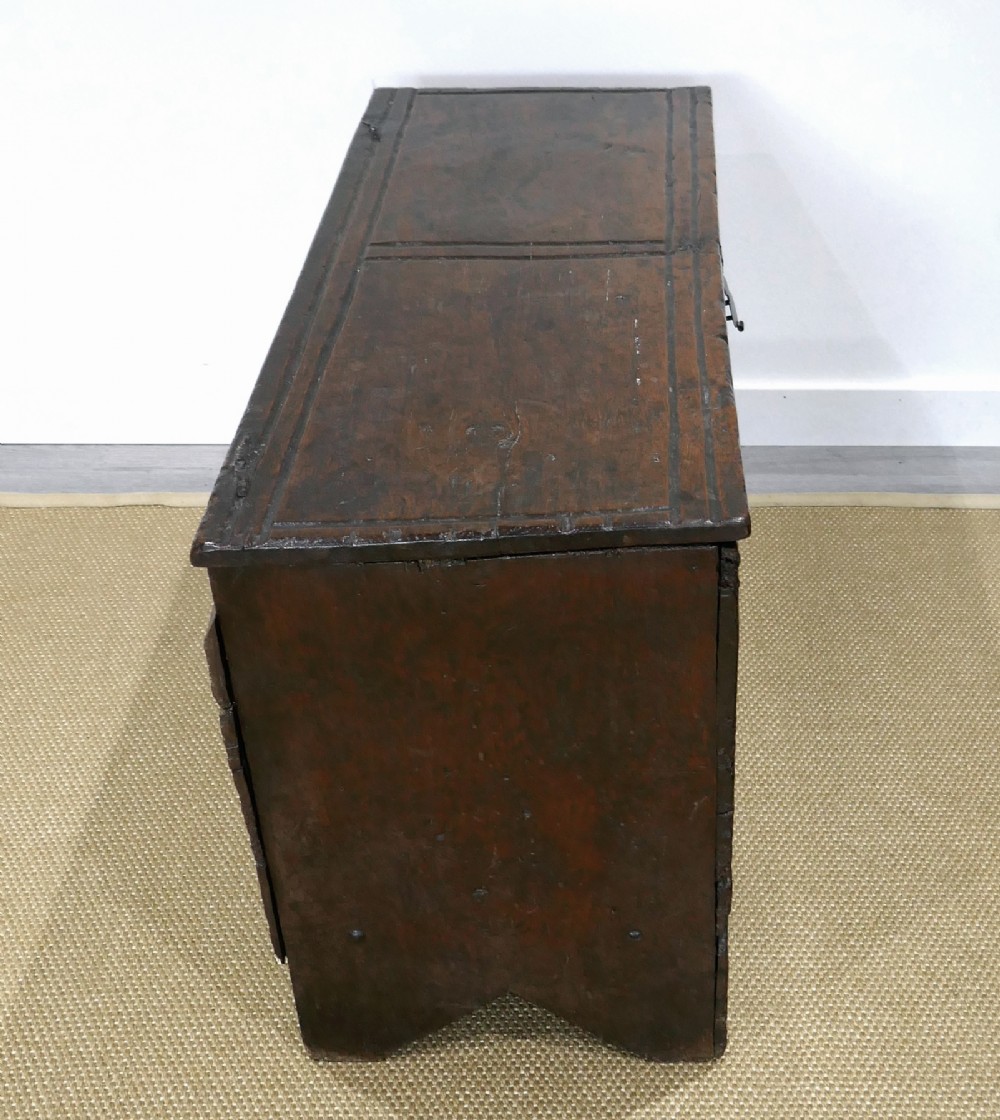 A sixteenth-century dark oak boarded coffer featuring a simple flat lid, an iron lockplate on the front panel, and a shaped lower apron. View VIII