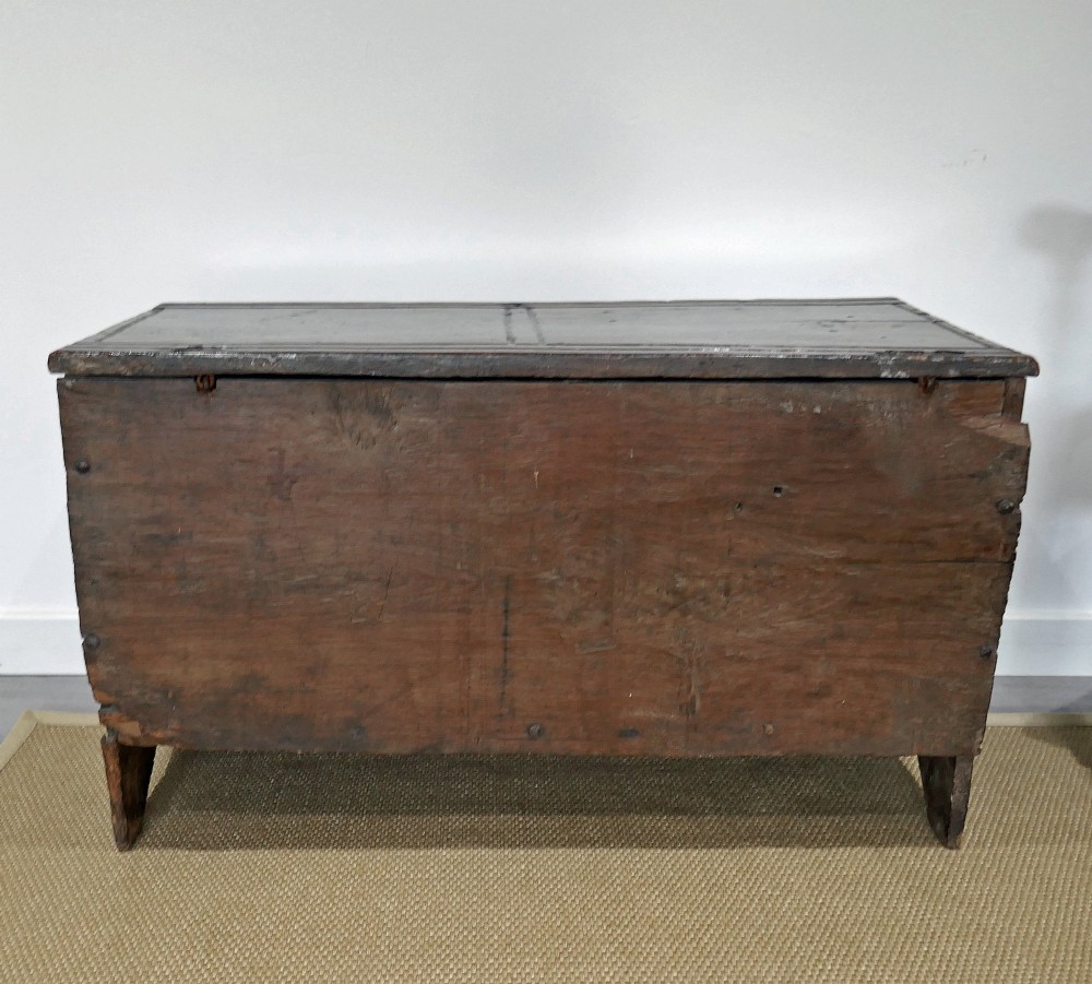A sixteenth-century dark oak boarded coffer featuring a simple flat lid, an iron lockplate on the front panel, and a shaped lower apron. View IX
