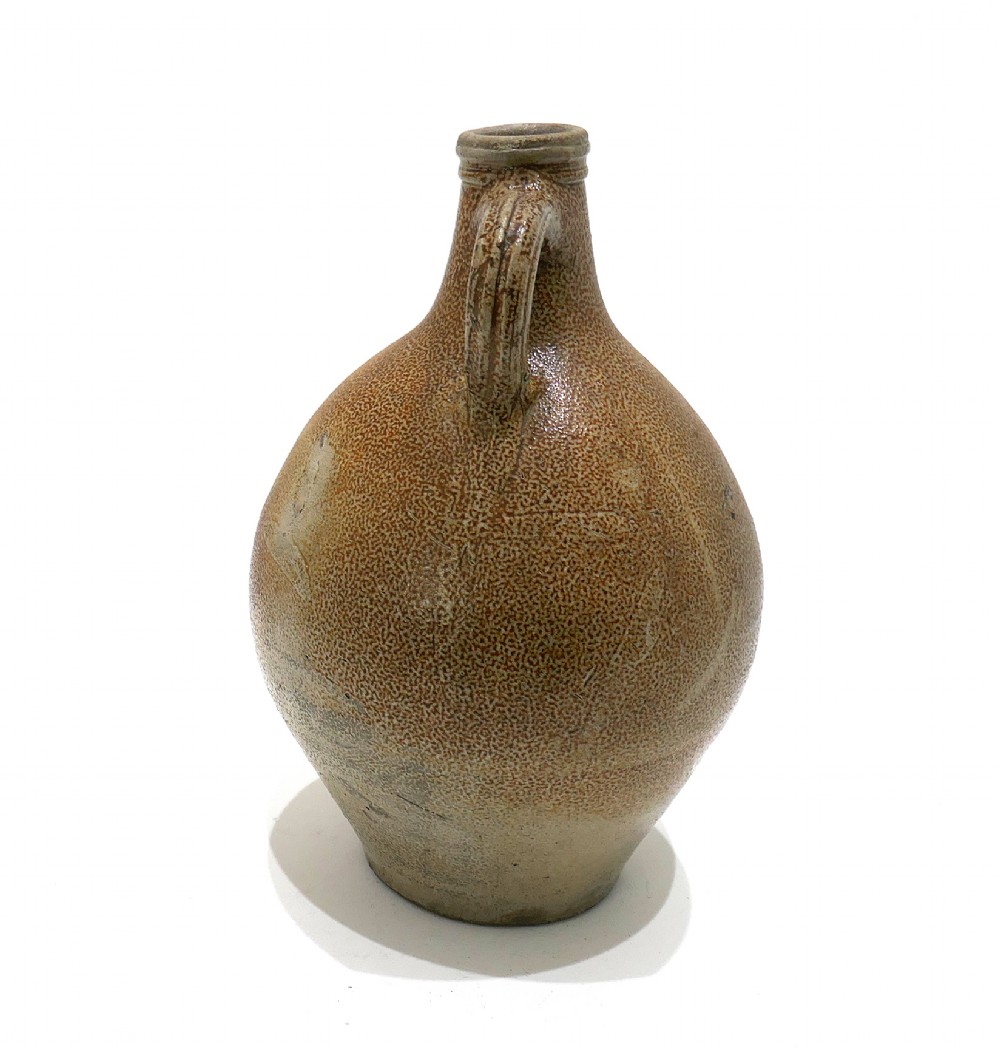 A 17th-century bulbous brown salt-glazed stoneware Bellarmine jug featuring a relief-carved bearded mask on the neck and decorative rosette medallions. View IV