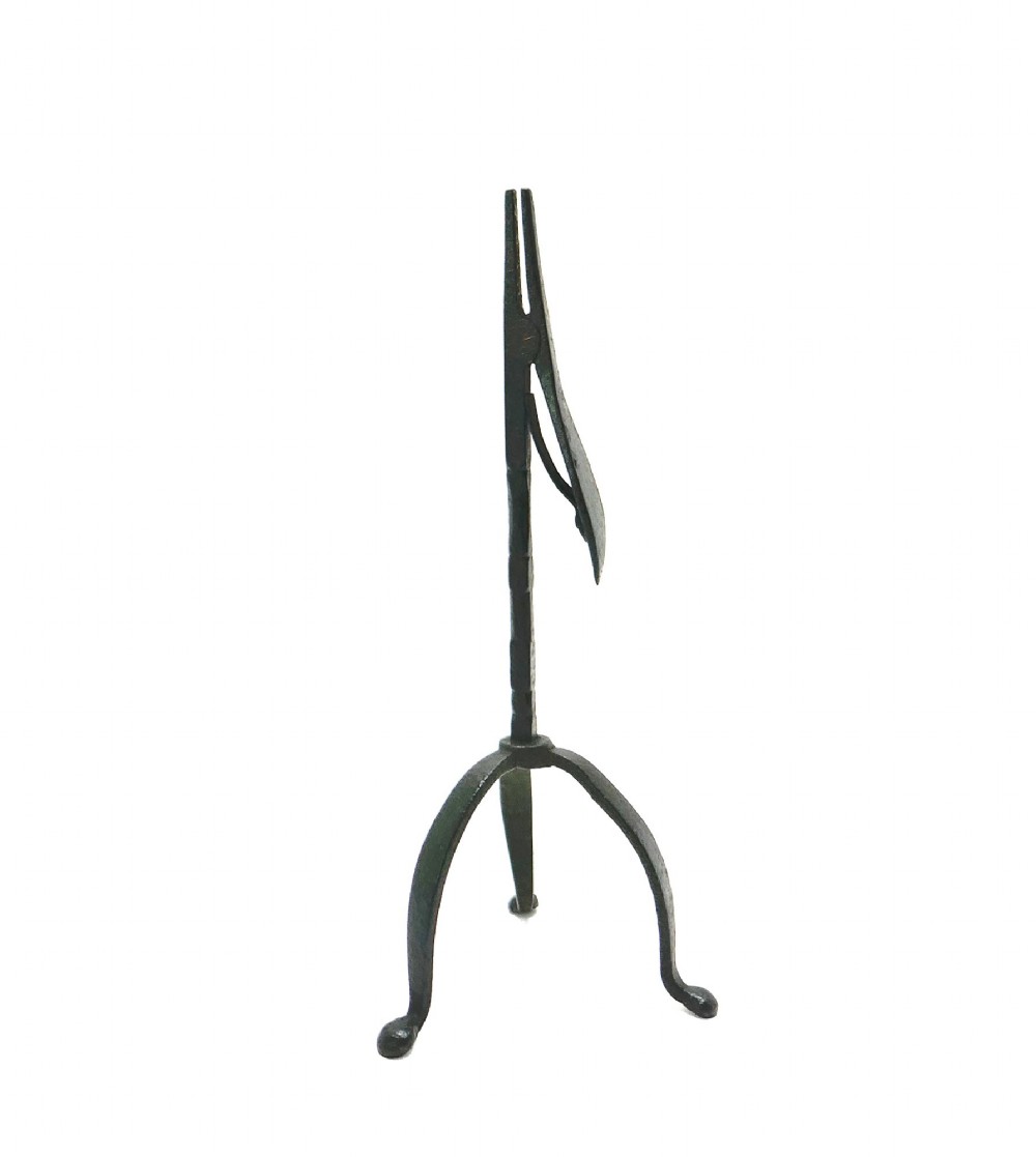 An eighteenth-century hand-forged wrought iron rushlight holder with a spring-action clamp and a tripod base.