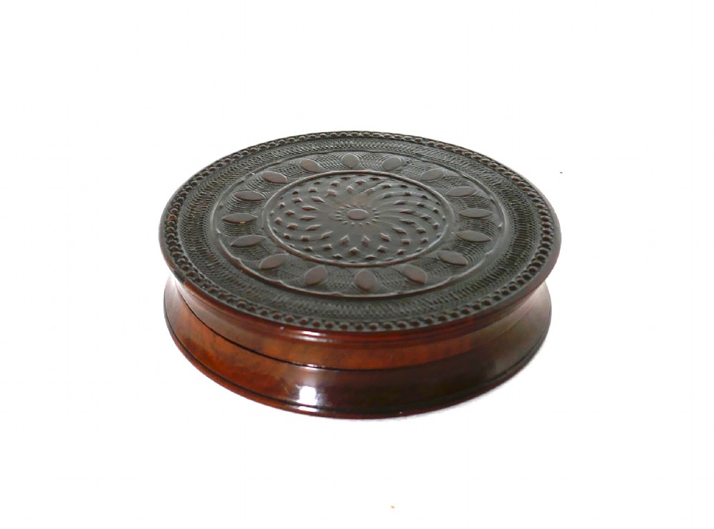 A circular early 19th-century dark laburnum wood snuff box featuring engine-turned geometric pattern carving on the lid.