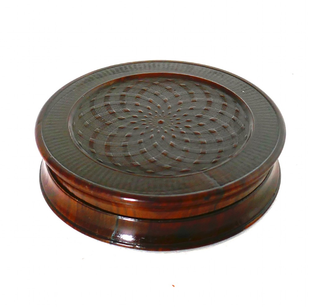 A circular early 19th-century dark laburnum wood snuff box featuring engine-turned geometric pattern carving on the lid. View II