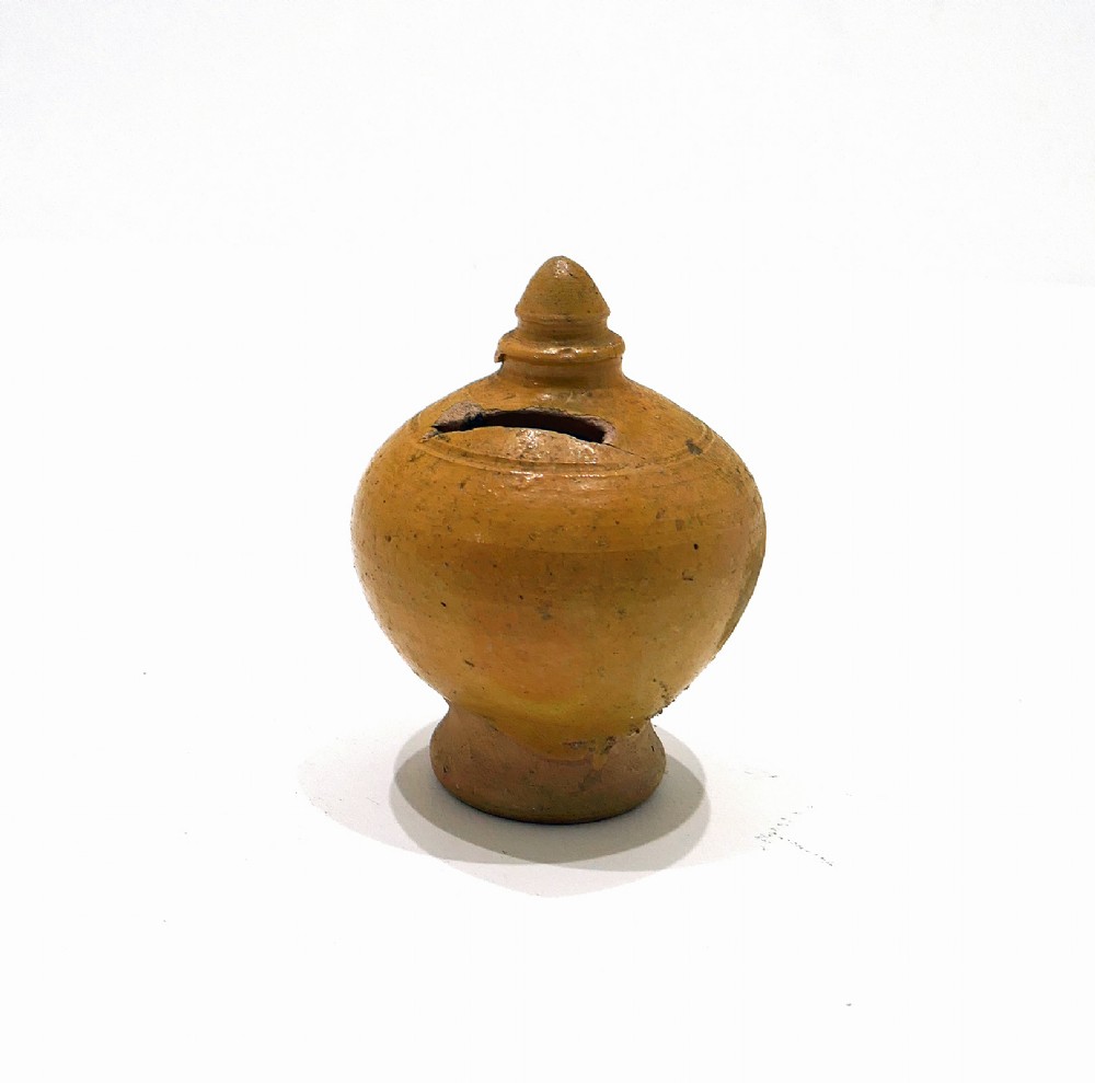 A nineteenth-century yellow glazed earthenware money box featuring a bulbous body, pointed finial, and coin slot near the top.