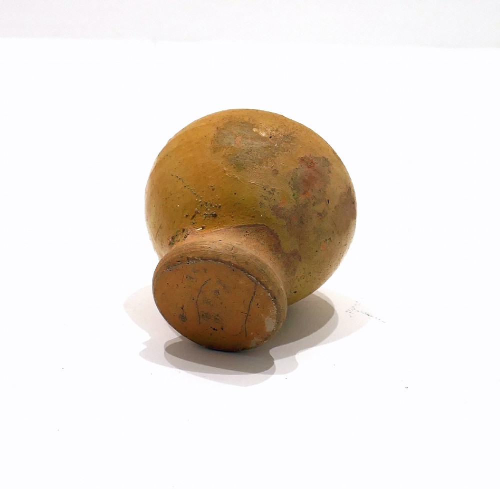A nineteenth-century yellow glazed earthenware money box featuring a bulbous body, pointed finial, and coin slot near the top. View IV