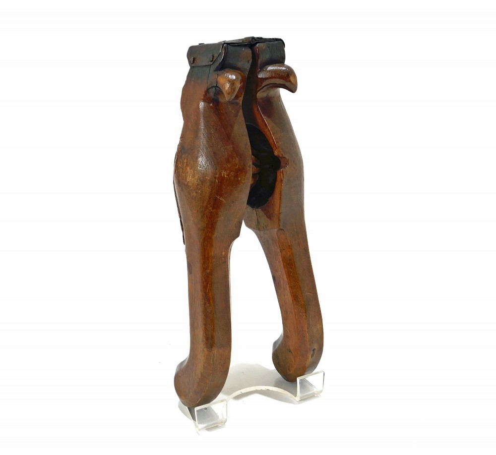 A 19th-century carved sycamore lemon squeezer shaped as two falcon heads with a hinged top and dark wood patina.