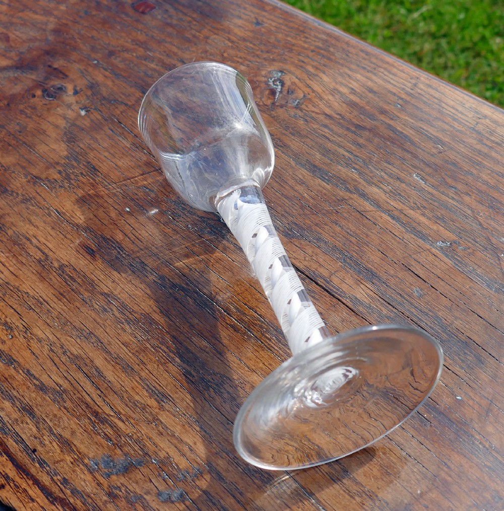 An eighteenth-century clear lead glass wine glass featuring an ogee bowl, an opaque white twist stem, and a conical foot. View III