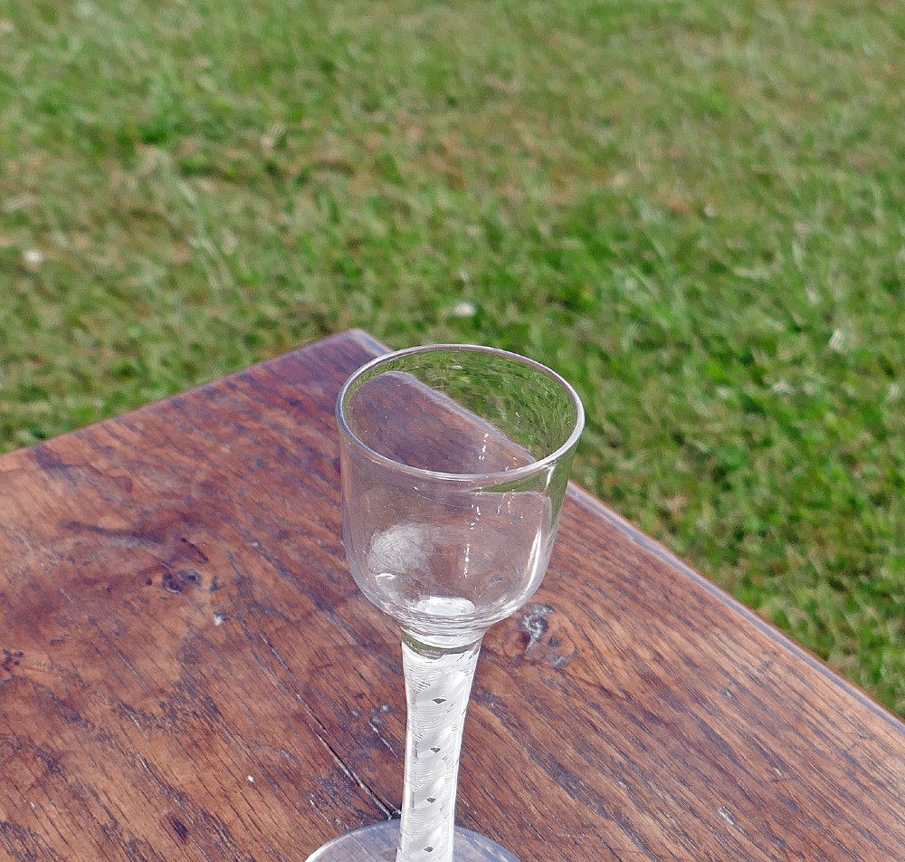 An eighteenth-century clear lead glass wine glass featuring an ogee bowl, an opaque white twist stem, and a conical foot. View IV