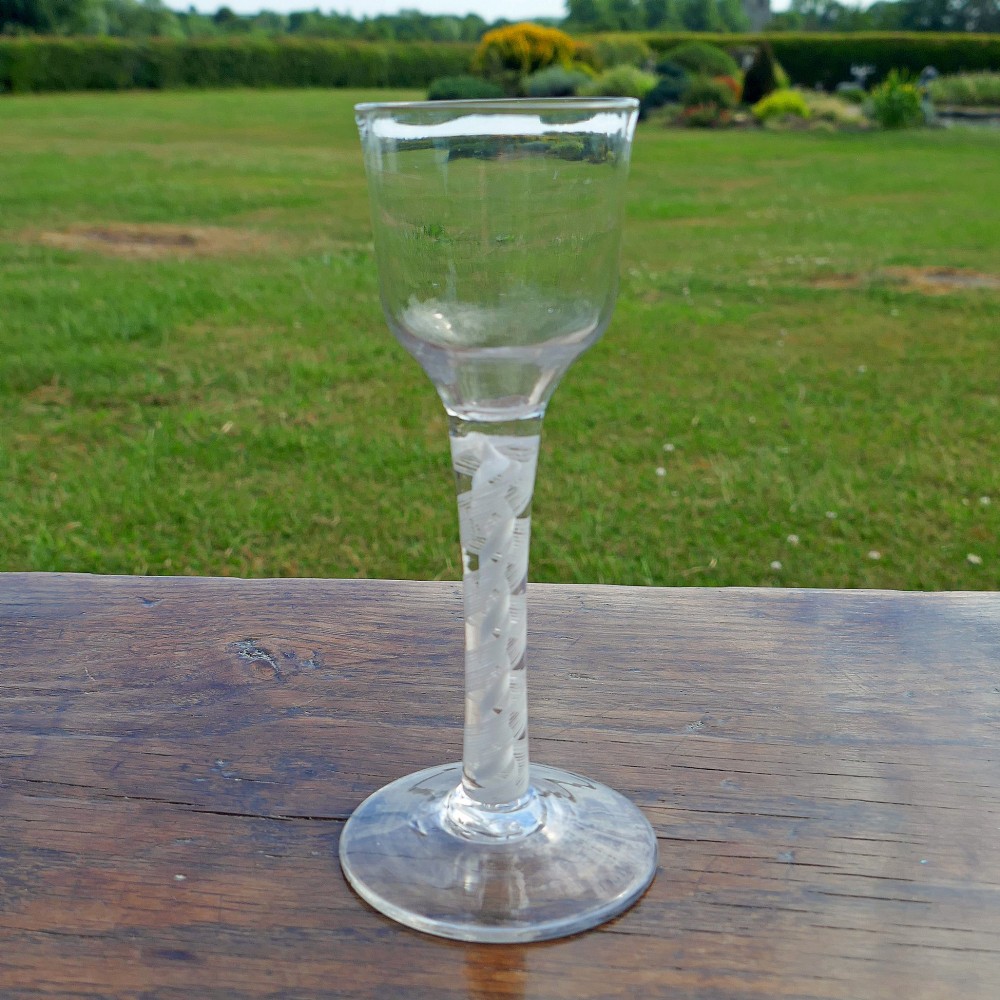 An eighteenth-century clear lead glass wine glass featuring an ogee bowl, an opaque white twist stem, and a conical foot. View V
