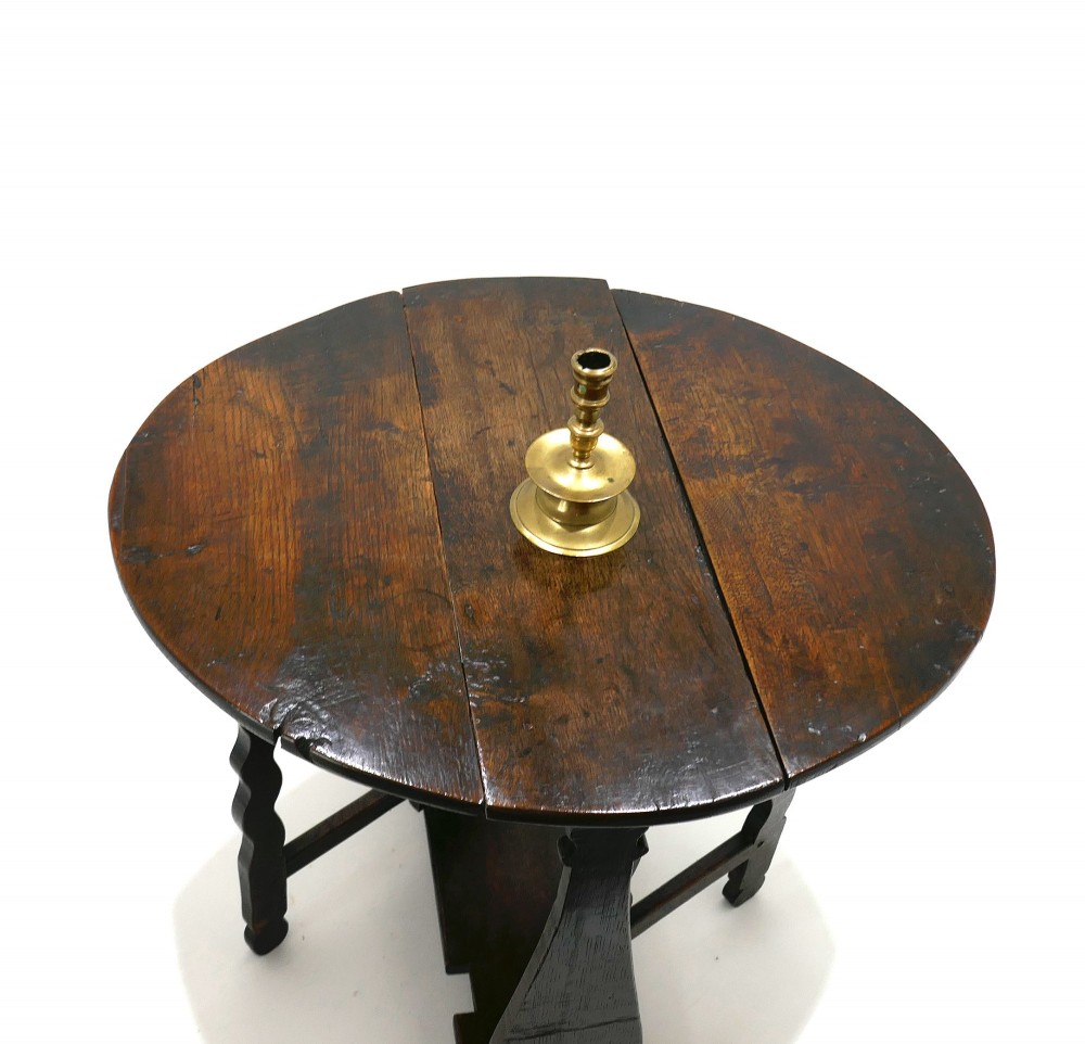 A seventeenth-century English dark oak gateleg table featuring a rounded drop-leaf top supported by shaped gates and trestle feet. View II