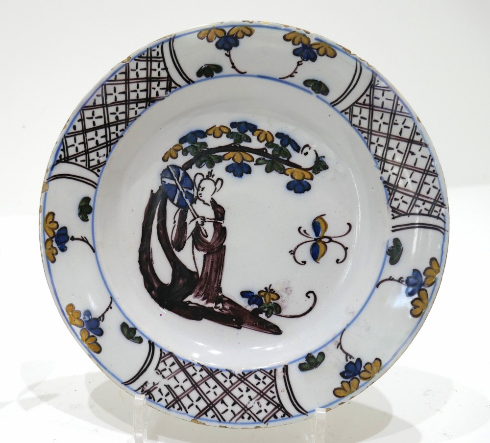 A pair of 18th-century circular tin-glazed earthenware plates decorated with hand-painted polychrome chinoiserie figures and floral rim borders. View II