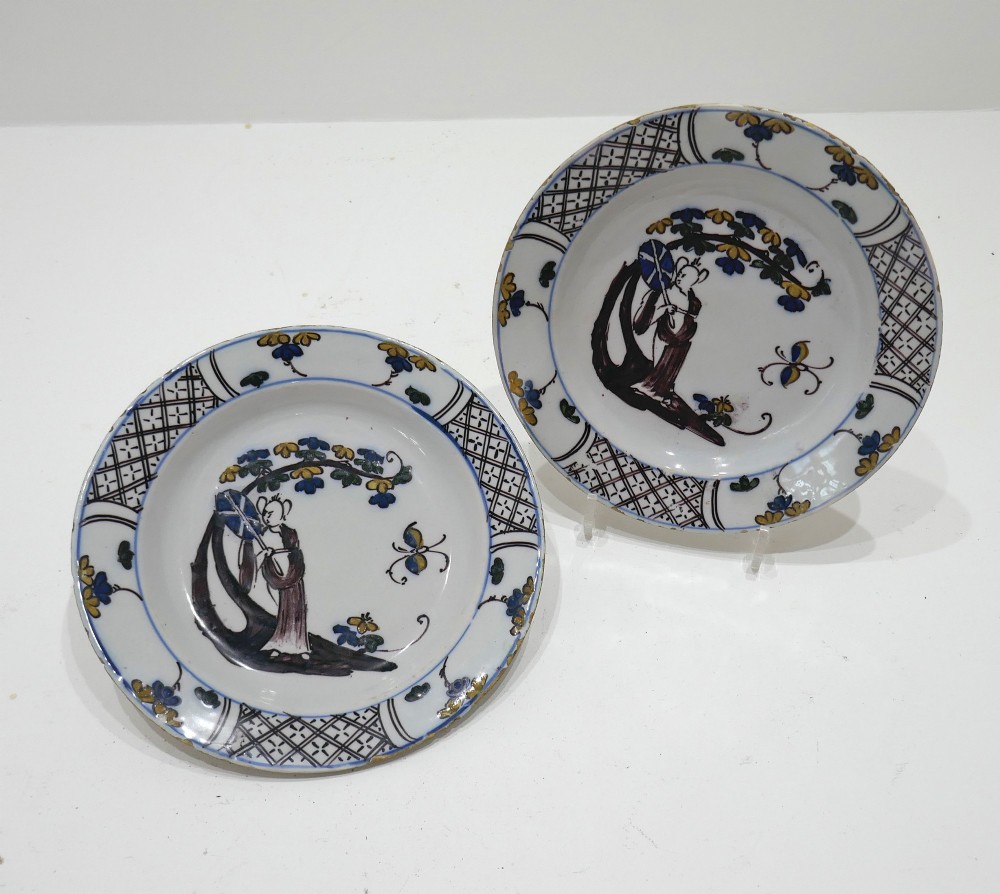 A pair of 18th-century circular tin-glazed earthenware plates decorated with hand-painted polychrome chinoiserie figures and floral rim borders. View V