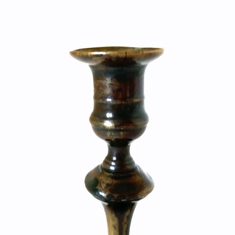 An eighteenth-century cast brass candlestick featuring a baluster stem and a scalloped base with dark surface patina. View VI
