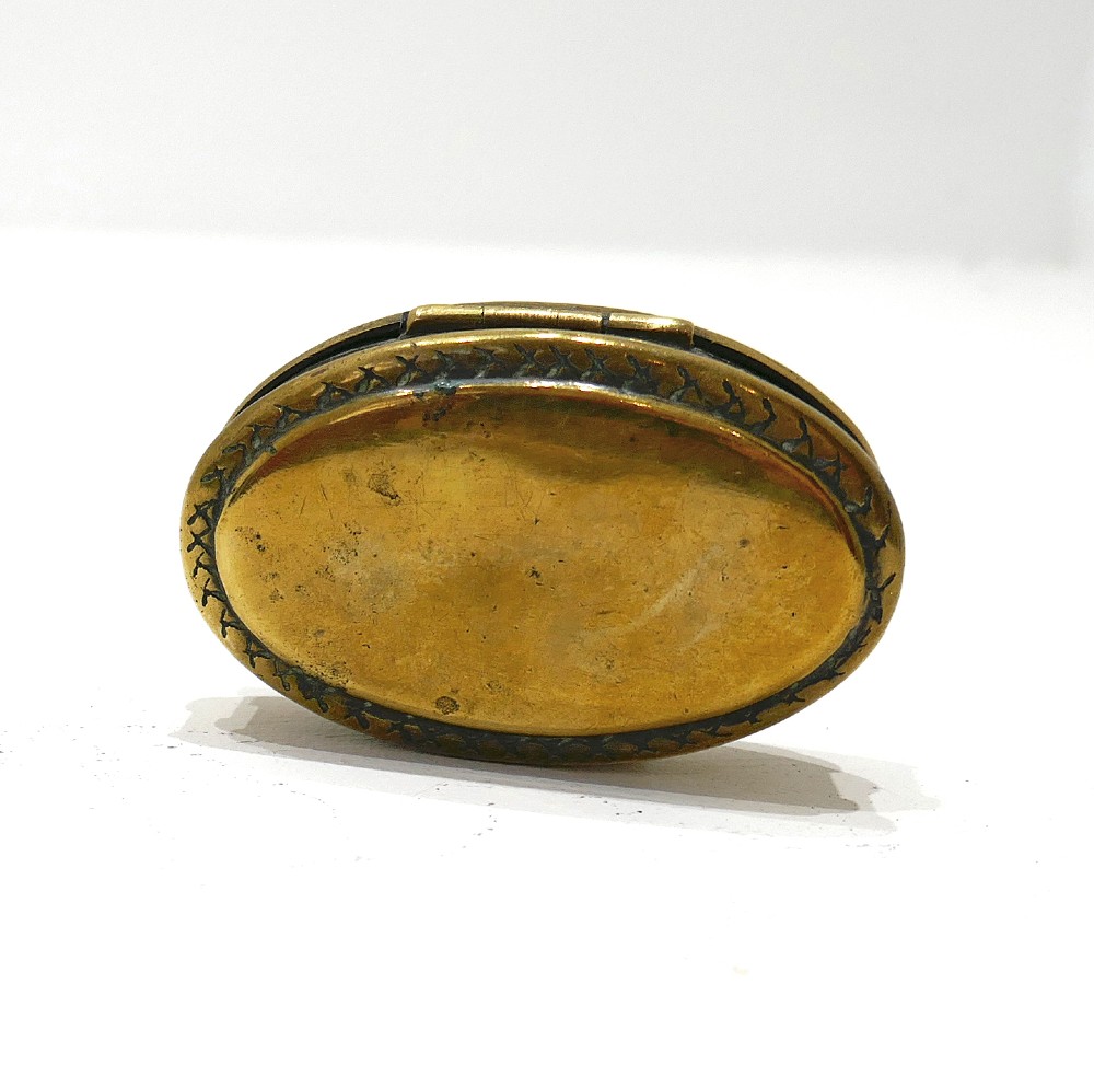 An oval brass snuff box featuring hand-engraved text that reads Ted Feltham 1911 Carter Frome surrounded by small hammer motifs and decorative border crosshatching. View II