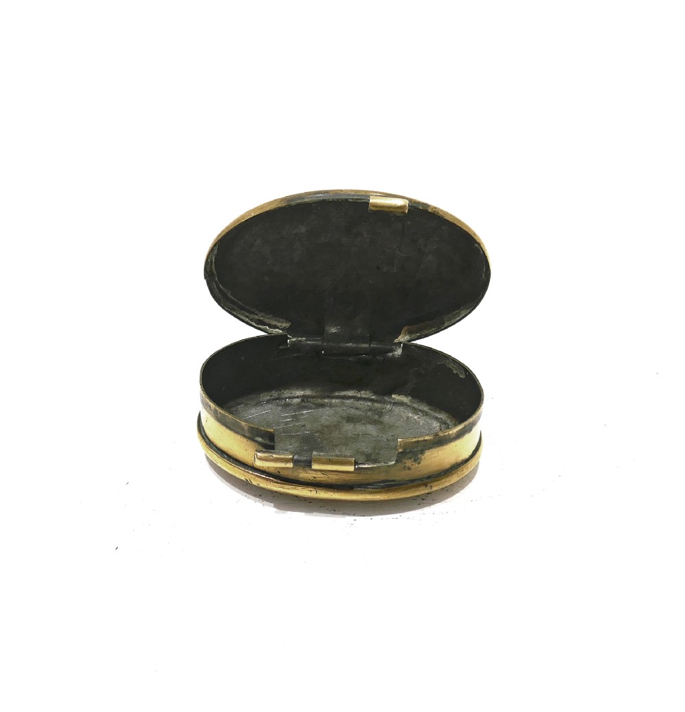 An oval brass snuff box featuring hand-engraved text that reads Ted Feltham 1911 Carter Frome surrounded by small hammer motifs and decorative border crosshatching. View V