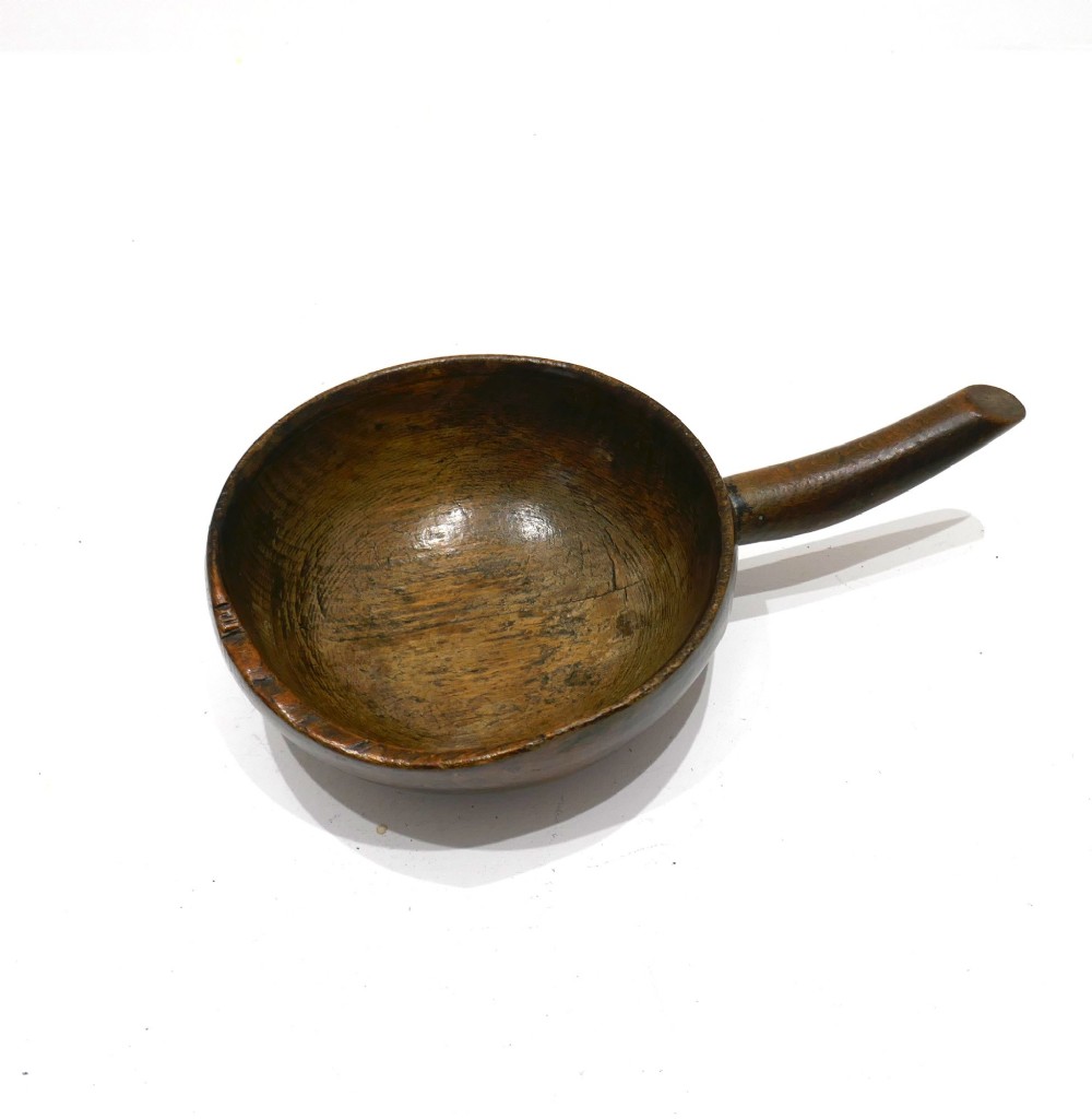 A turned 19th-century dark beechwood dairy bowl with a carved lateral handle and a shallow dished basin.