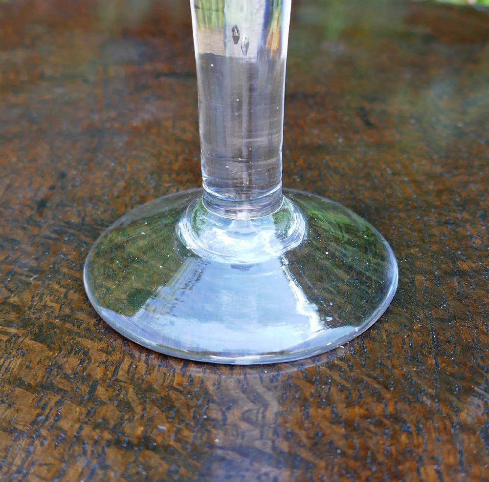 An 18th-century clear hand-blown glass wine goblet with a trumpet bowl, a drawn stem featuring a central teardrop air bubble, and a flat conical base. View II