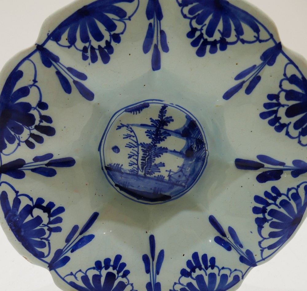 An antique 17th-century English tin-glazed earthenware lobed dish featuring hand-painted cobalt blue floral panels and a central landscape scene. View II