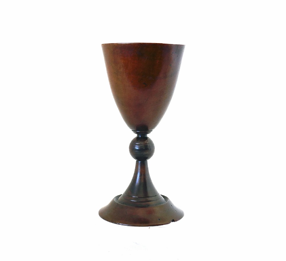 A hand-turned early 19th-century fruitwood goblet featuring a flared bowl, knopped stem, and circular pedestal base with a dark polished patina.