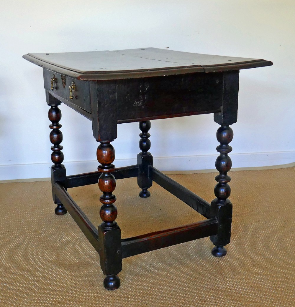 A 17th-century English oak side table featuring a single drawer with brass drop handles, turned ball legs, and a perimeter stretcher base. View V