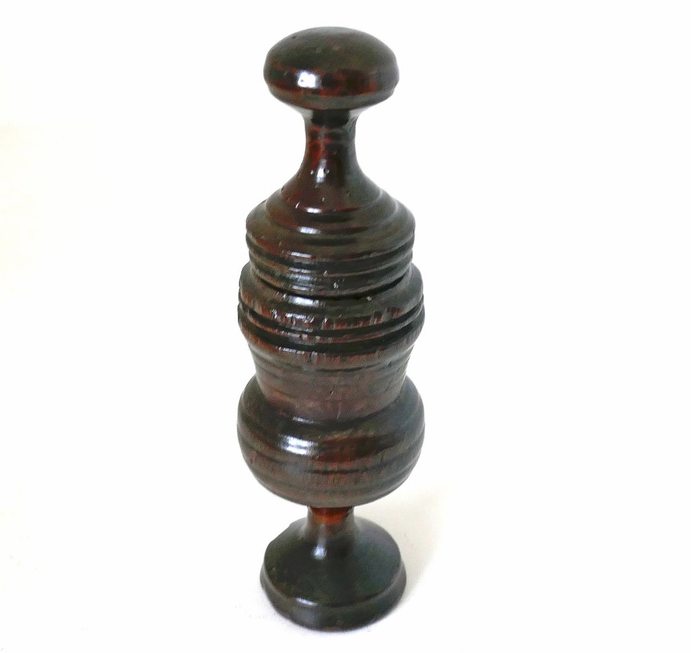 A turned dark sycamore wood two-part spice grinder featuring a baluster-shaped body, ribbed tiering, and a round finial top.