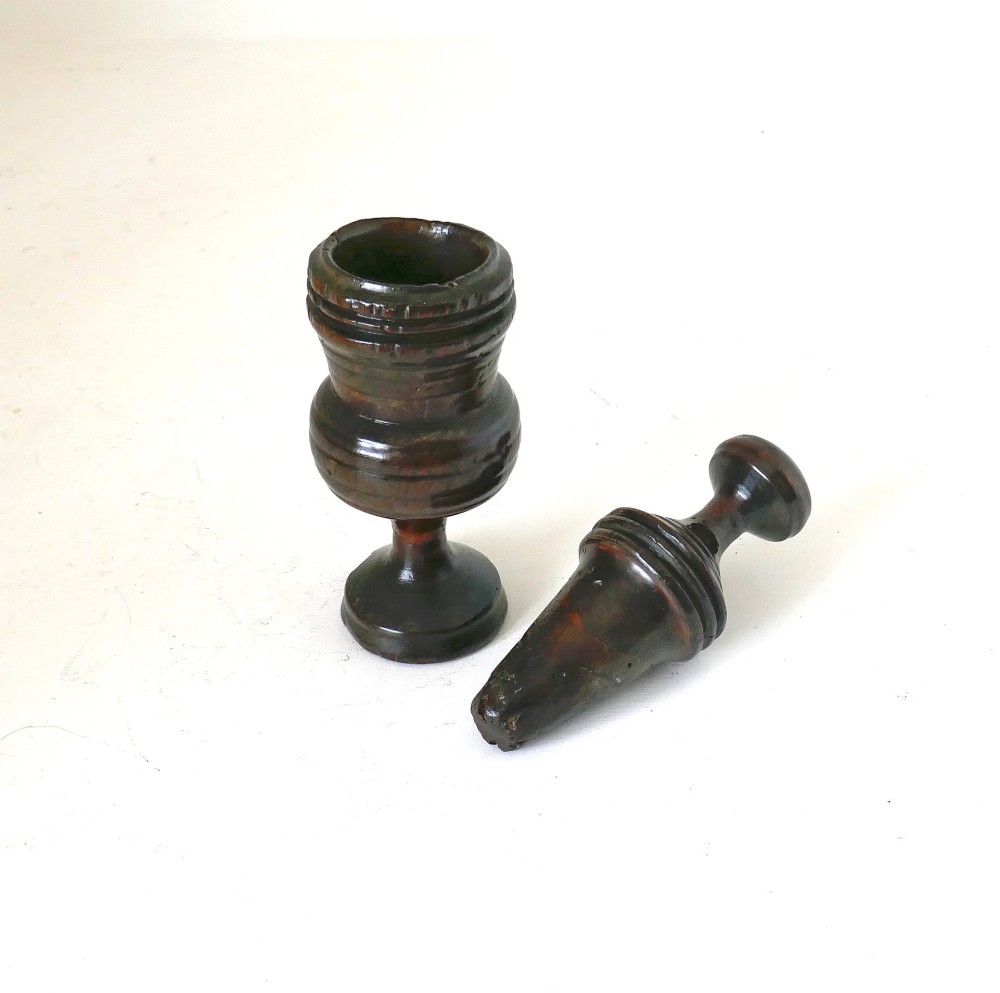 A turned dark sycamore wood two-part spice grinder featuring a baluster-shaped body, ribbed tiering, and a round finial top. View II
