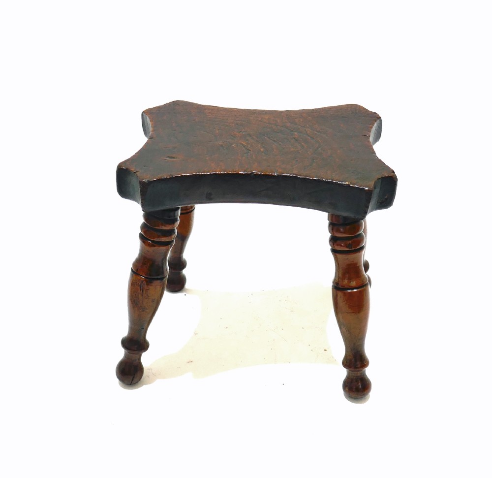 A nineteenth-century dark ash and elm lacemakers stool featuring a thick contoured rectangular seat and four turned wood legs. View III