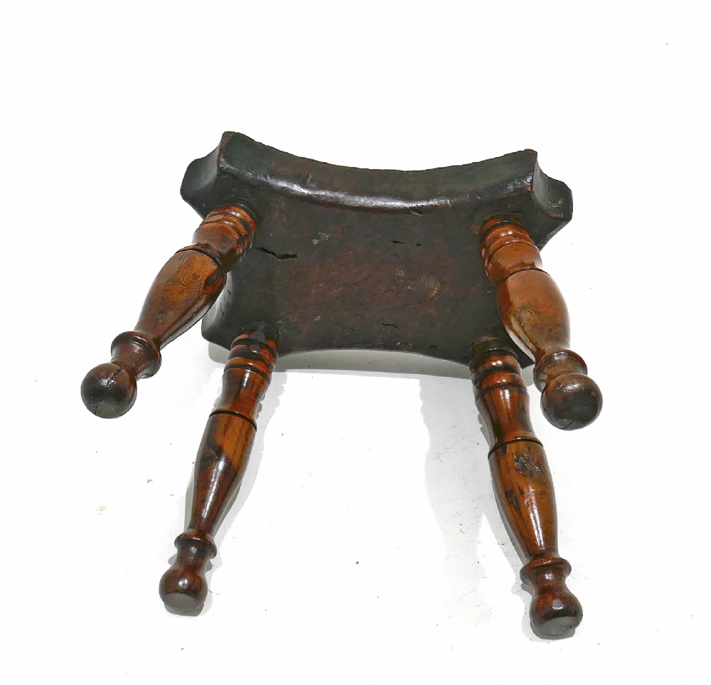 A nineteenth-century dark ash and elm lacemakers stool featuring a thick contoured rectangular seat and four turned wood legs. View V