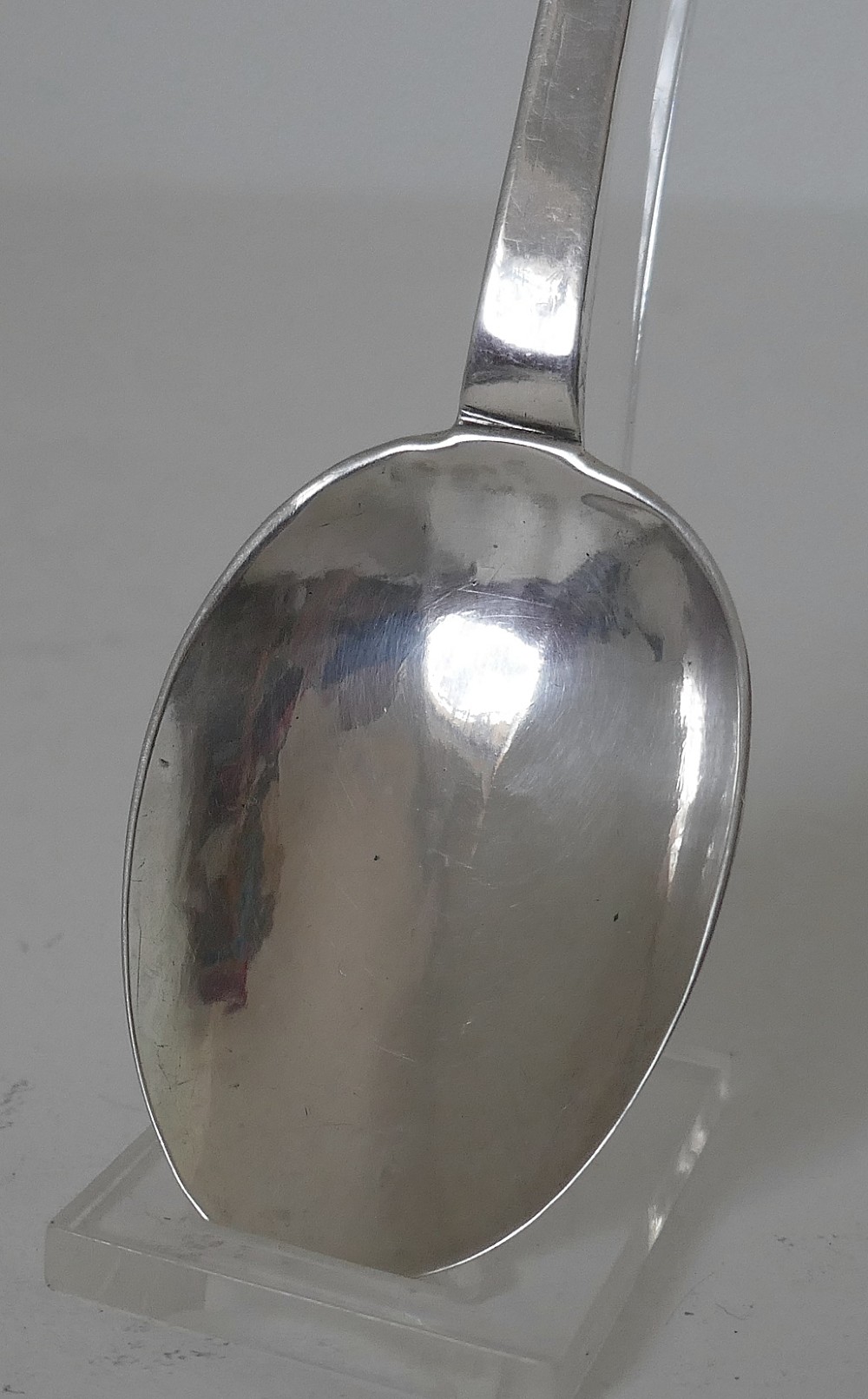 A 17th-century English sterling silver trefid spoon with a lobed terminal handle and an oval bowl displayed on a clear stand. View VI