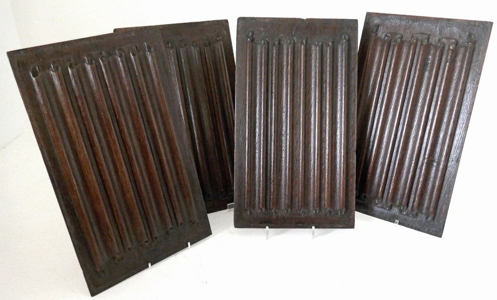 A set of four dark oak rectangular panels featuring hand-carved vertical linenfold drapery design.
