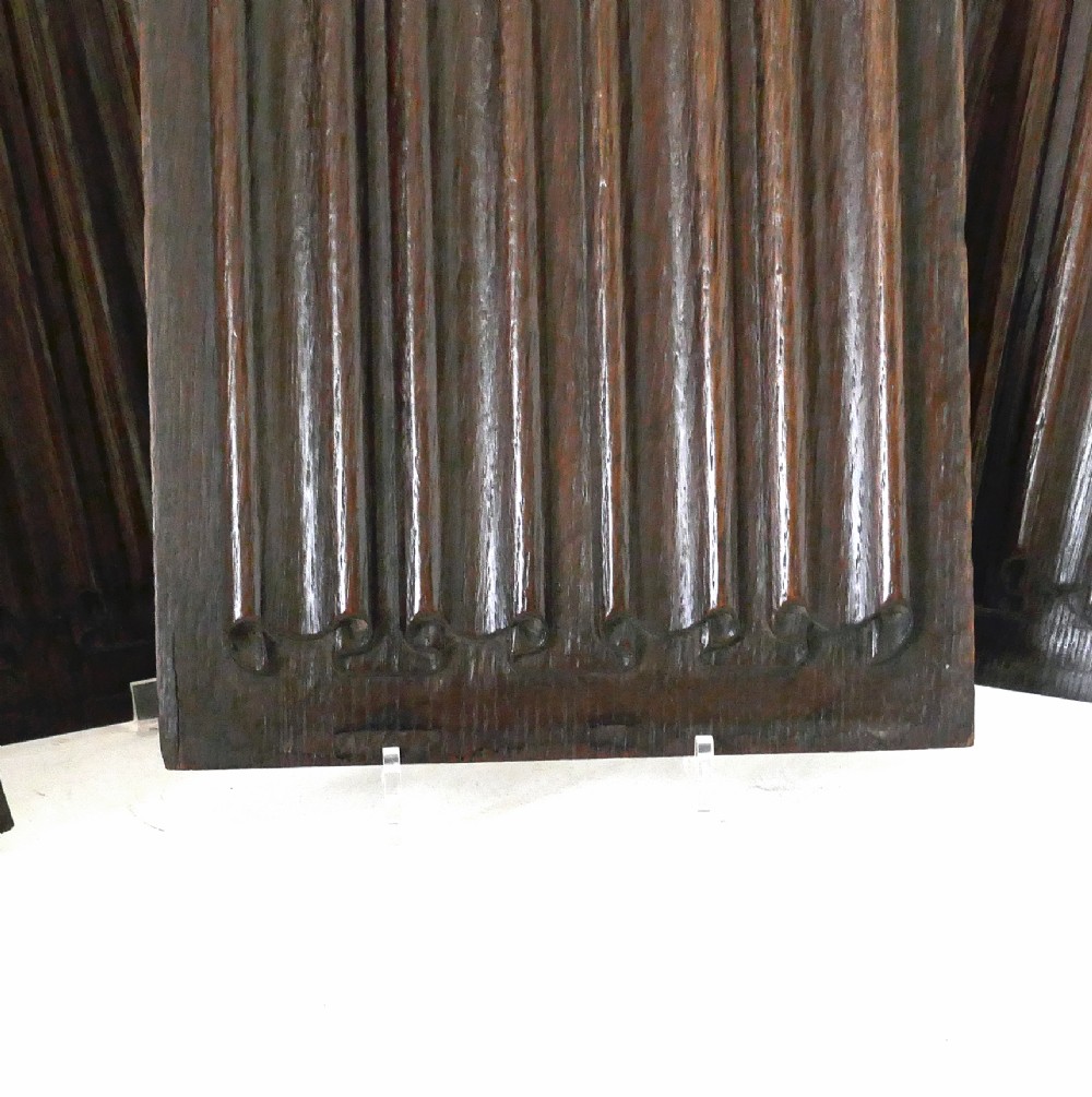 A set of four dark oak rectangular panels featuring hand-carved vertical linenfold drapery design. View II