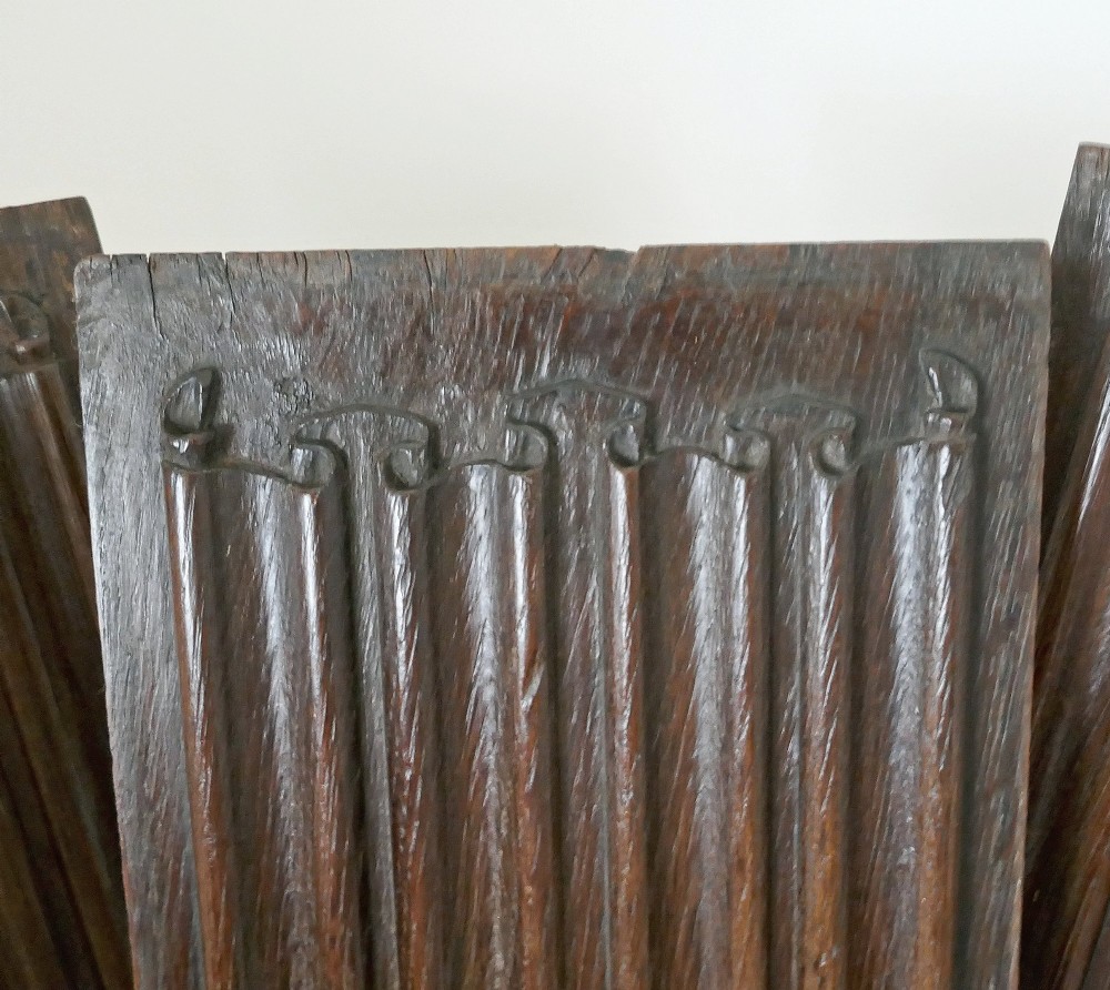 A set of four dark oak rectangular panels featuring hand-carved vertical linenfold drapery design. View III