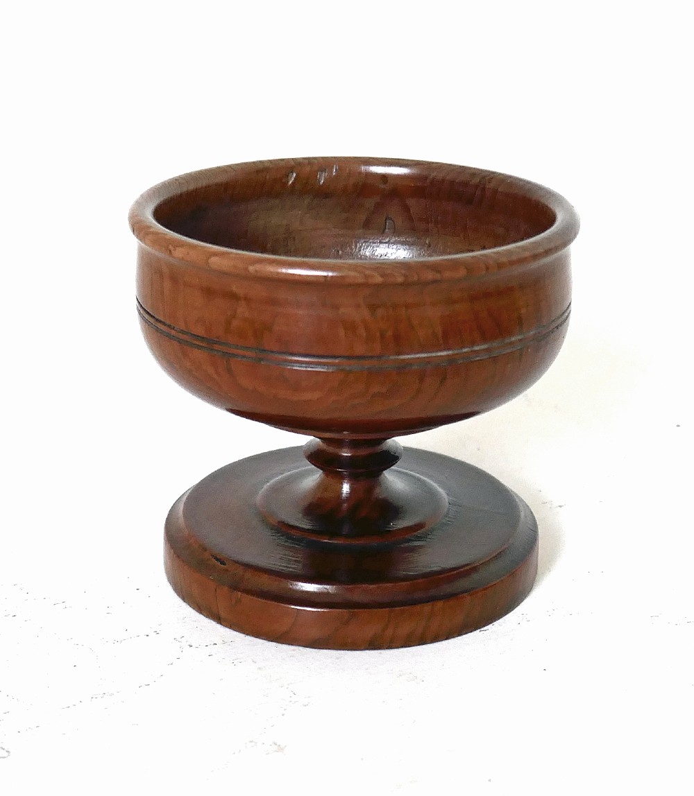 An 18th-century turned yew wood salt cellar featuring a bowl-shaped top set on a short pedestal stem and circular stepped base. View V