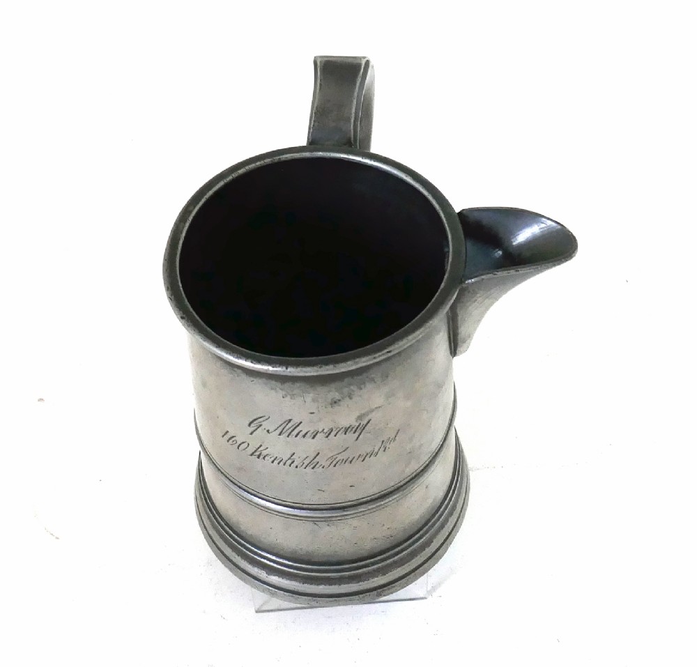 An antique 19th-century pewter ale jug featuring cursive inscription engraving, a pinched pour spout, and a moulded flared base. View VI