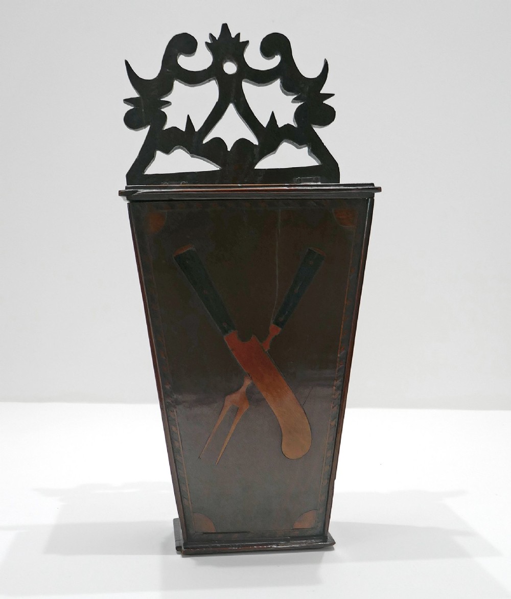 A wall-hanging Georgian mahogany cutlery box featuring a pierced cresting rail and inlaid crossed knife and fork pattern in boxwood and ebony.