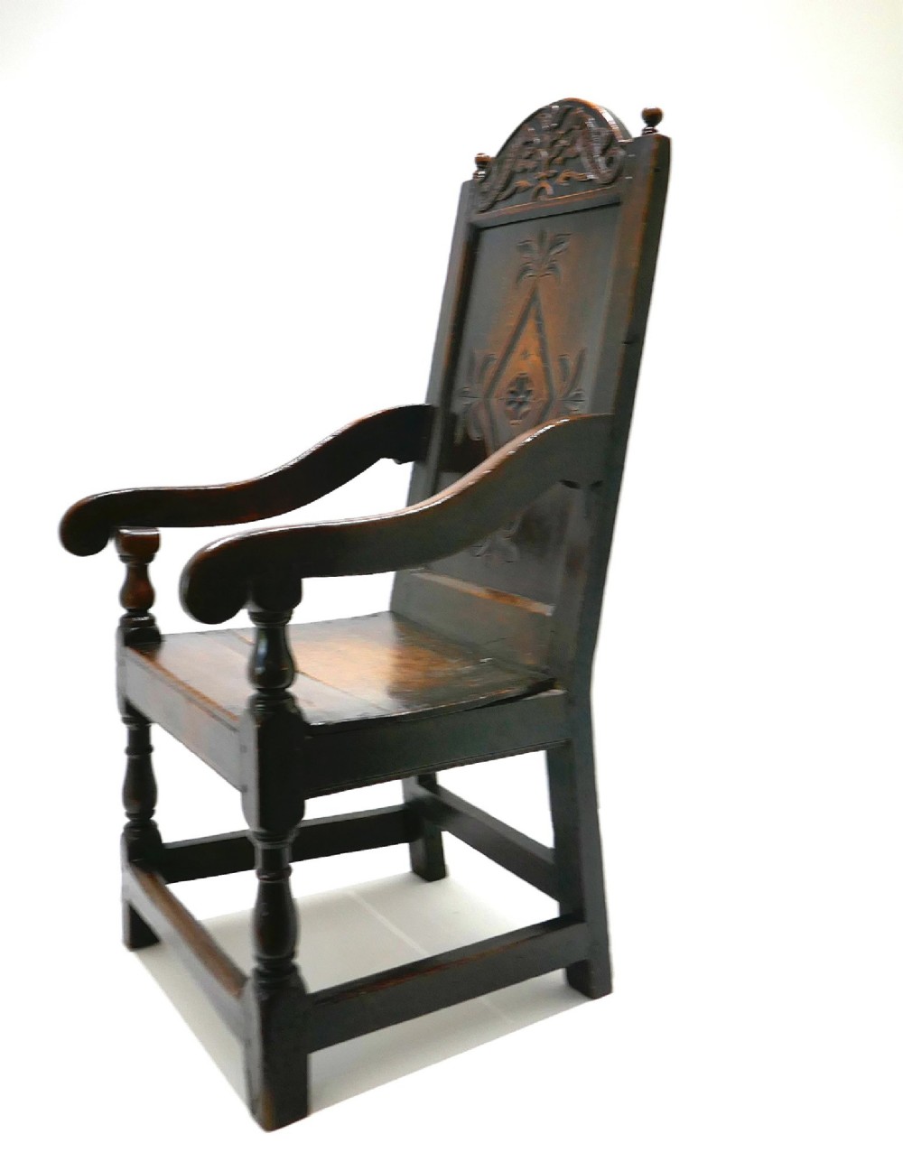 A 17th-century dark oak joined wainscot armchair featuring a carved lozenge back panel, turned front legs, scrolled arms, and a carved top rail. View IV