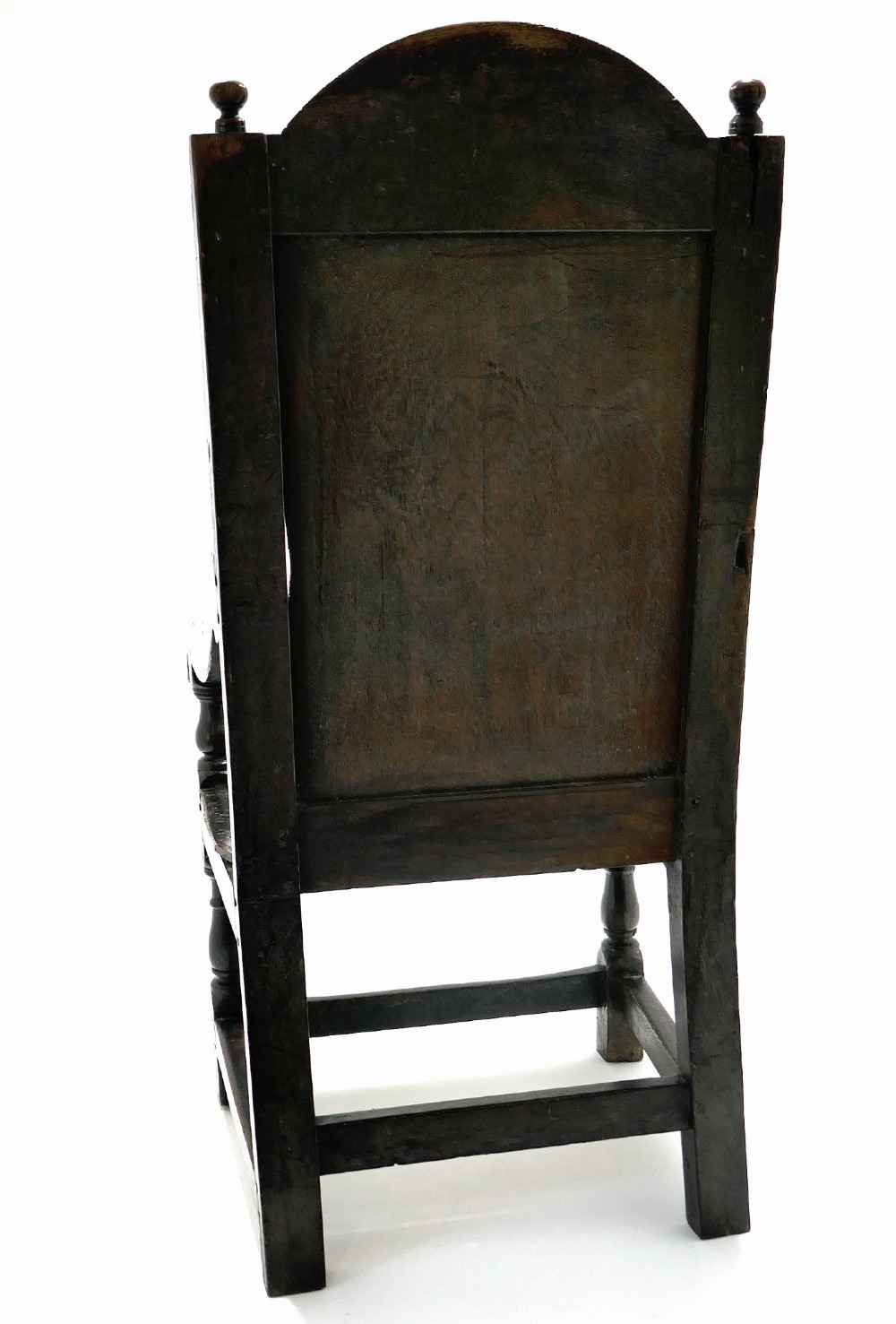 A 17th-century dark oak joined wainscot armchair featuring a carved lozenge back panel, turned front legs, scrolled arms, and a carved top rail. View V