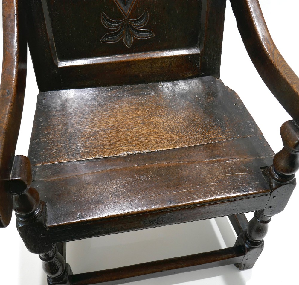 A 17th-century dark oak joined wainscot armchair featuring a carved lozenge back panel, turned front legs, scrolled arms, and a carved top rail. View VII