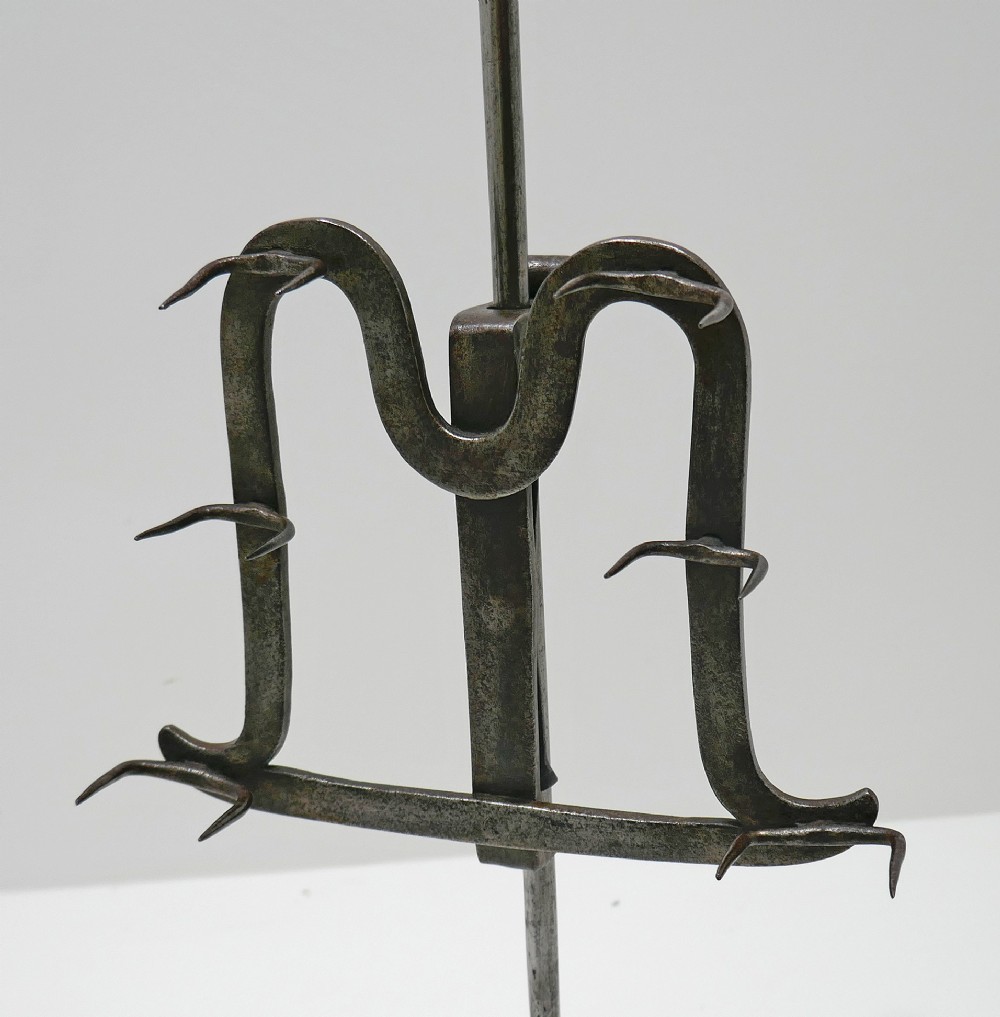 An eighteenth-century wrought iron adjustable lark spit toaster featuring a tripod base with rolled feet, a central vertical stem, and six pointed prongs. View III