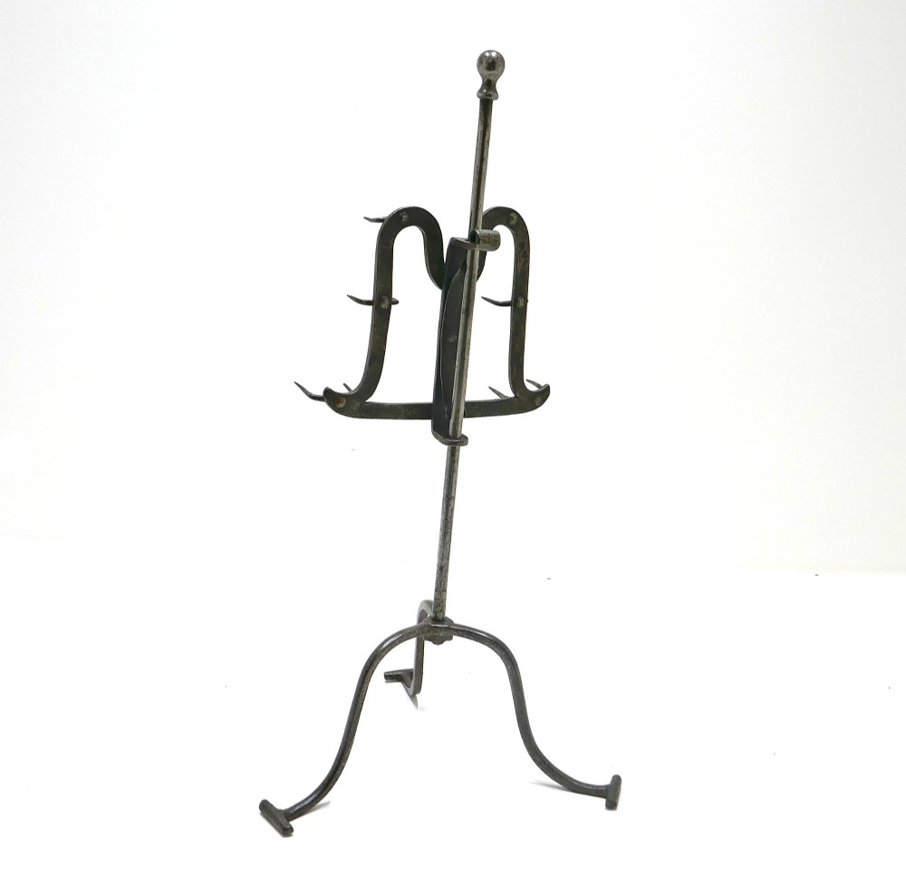 An eighteenth-century wrought iron adjustable lark spit toaster featuring a tripod base with rolled feet, a central vertical stem, and six pointed prongs. View V
