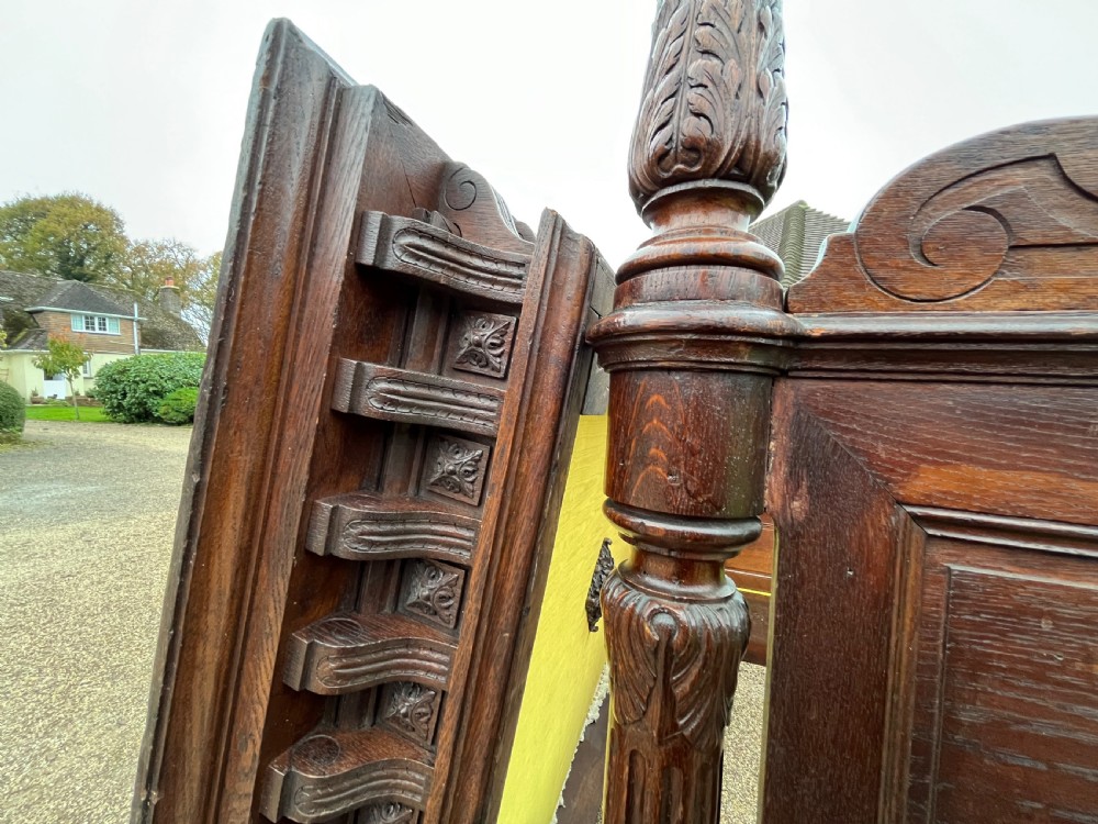 A dark carved oak four poster bed featuring turned columns, an ornate carved headboard, and a gold fabric-lined canopy. View III